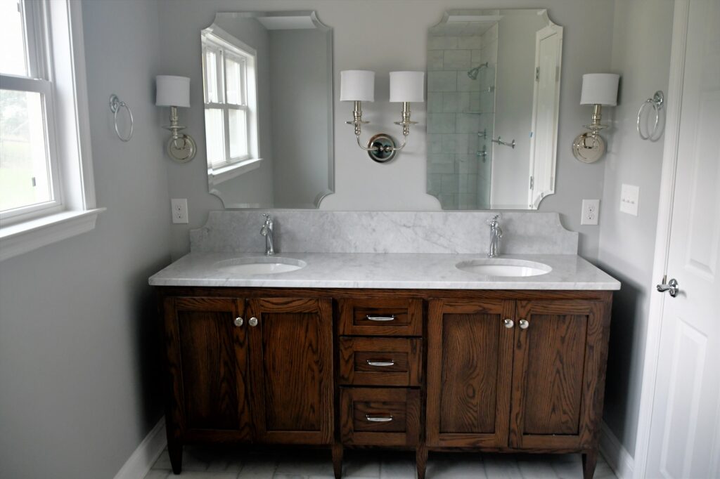 Clean bright bathroom with dark wood vanity and white marble sinks in a new home or after a remodel