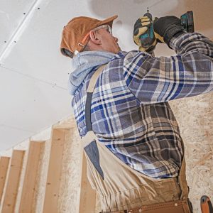 Construction Contractor Attaching Drywall Elements to the House Ceiling